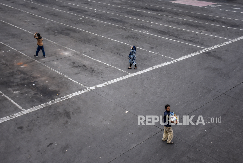 Sejumlah warga berjalan di area parkiran bus yang kosong di Terminal Cicaheum, Kota Bandung, Jumat (7/5). Meski sudah memberlakukan larangan mudik, pemerintah tetap bersiap menghadapi kemungkinan lonjakan kasus Covid-19 pascalibur Lebaran.