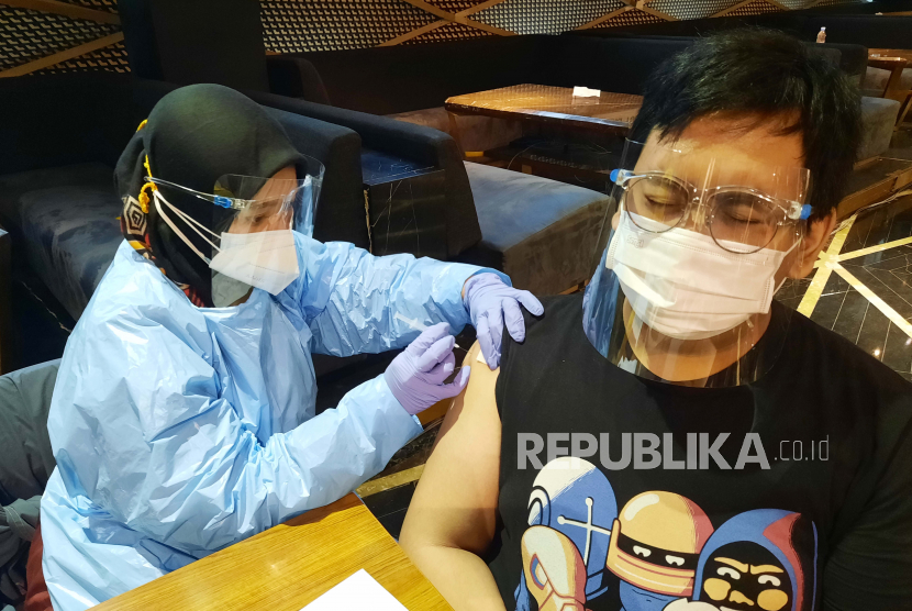 Seorang pria menerima dosis vaksin COVID-19 selama vaksinasi massal.  Vaksinasi Covid-19 di Indonesia sudah dimulai sejak Januari 2021 lalu namun banyak orang yang sudah divaksin terpapar virus. Vaksinolog Dirga Sakti Rambe menjelaskan, meski vaksinasi Covid-19 telah dilakukan tidak menjamin bebas dari penularan Covid-19.