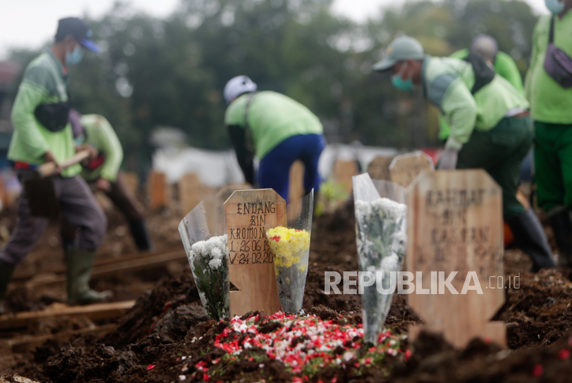 Para pekerja menggali kuburan saat pemakaman di Pemakaman Srengseng Sawah di Jakarta, 25 Februari 2021. Dana kematian covid dicabut pemerintah.