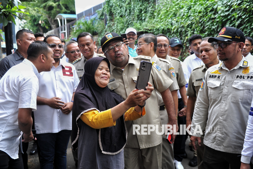 Wakil Gubernur DKI Jakarta Rano Karno (kiri) berswafoto dengan warga saat akan meninjau pengerukan lumpur Kali Krukut di kawasan Cilandak Timur, Jakarta, Jumat (21/2/2025).