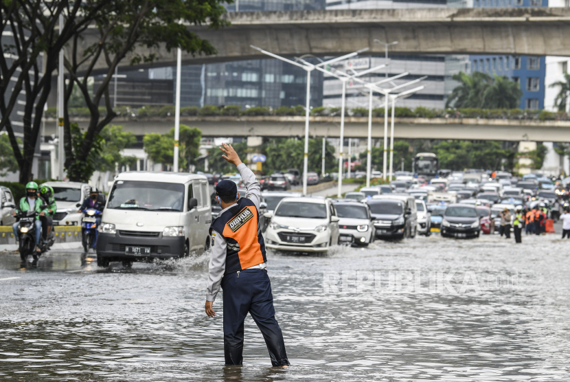 Petugas Dinas Perhubungan mengatur lalu lintas saat terjadinya banjir di kawasan Jalan Jenderal Sudirman, Jakarta, Sabtu (20/2). Badan Pengkajian dan Penerapan Teknologi (BPPT) menggunakan bahan semai 21,4 ton garam atau NaCl untuk mengurangi curah hujan yang turun di wilayah Jakarta, Bogor, Depok, Tangerang dan Bekasi (Jabodetabek).