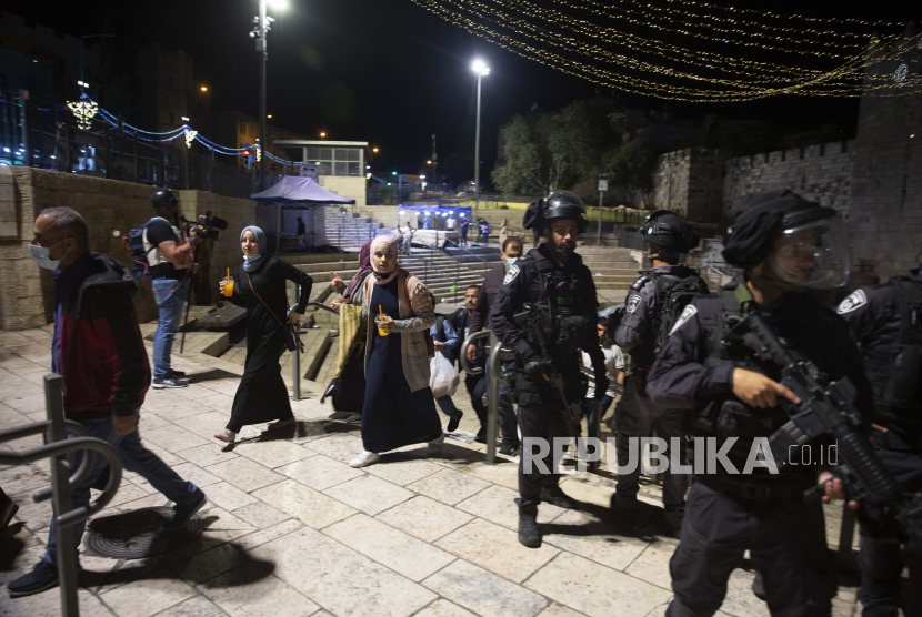  Wanita Palestina melewati barisan polisi Israel saat mereka meninggalkan Gerbang Damaskus ke Kota Tua Yerusalem setelah bentrokan di kompleks Masjid Al-Aqsa, Jumat, 7 Mei 2021. 