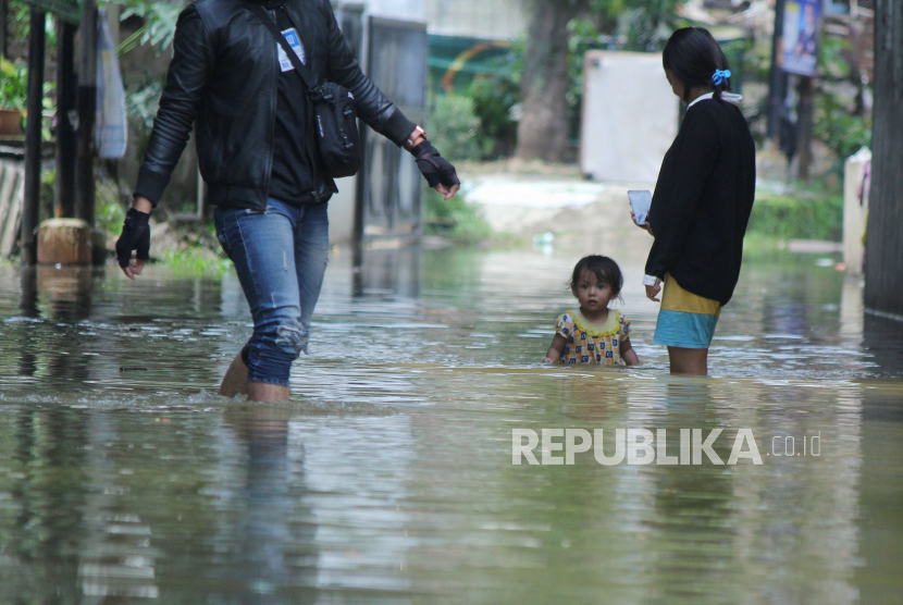 Warga melintasi jalan yang sudah tergenang banjir di kampung Bojongasih, Kecamatan Dayeuhkolot, Kabupaten Bandung