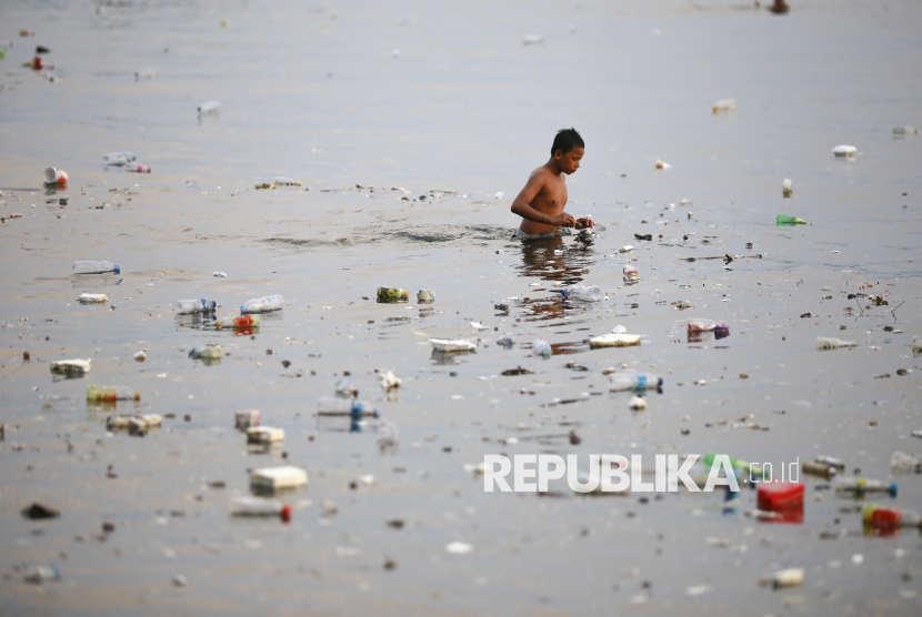 Seorang anak berenang di antara sampah yang mengapung di laut di Pantai Kalumata Ternate, Maluku Utara, Jumat (15/11/2024). 