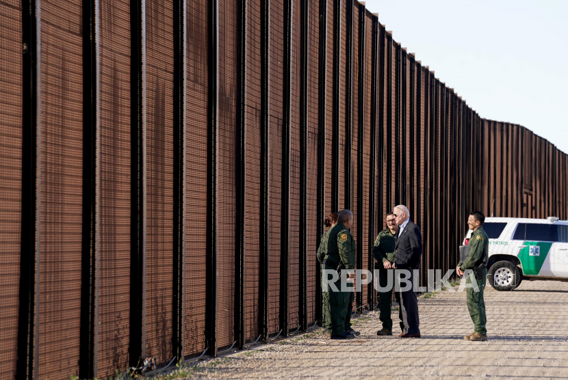  Presiden AS Joe Biden berbicara dengan petugas patroli perbatasan saat dia berjalan di sepanjang pagar perbatasan pada kunjungannya ke perbatasan AS-Meksiko untuk menilai operasi penegakan perbatasan, di El Paso, Texas, AS, Ahad (8/1/2023).