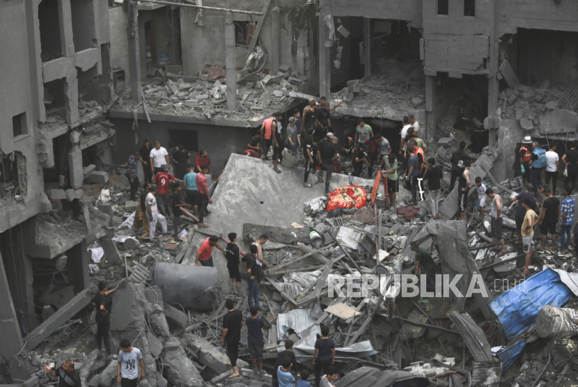 Warga Palestina memeriksa kerusakan bangunan yang hancur akibat serangan udara Israel di Kota Gaza, Jumat (27/2023).