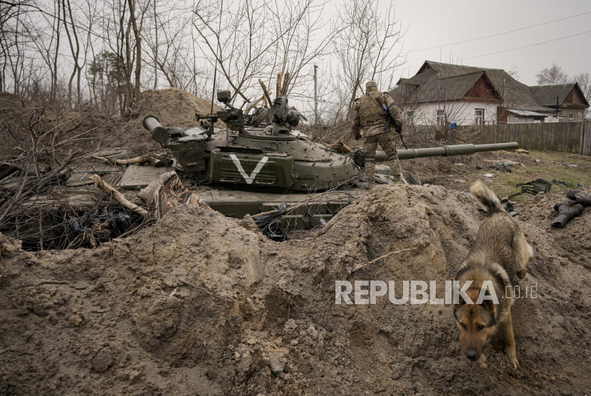 Seorang prajurit Ukraina berjalan di atas tank tentara Rusia yang ditinggalkan di Andriivka, Ukraina, 5 April 2022. 