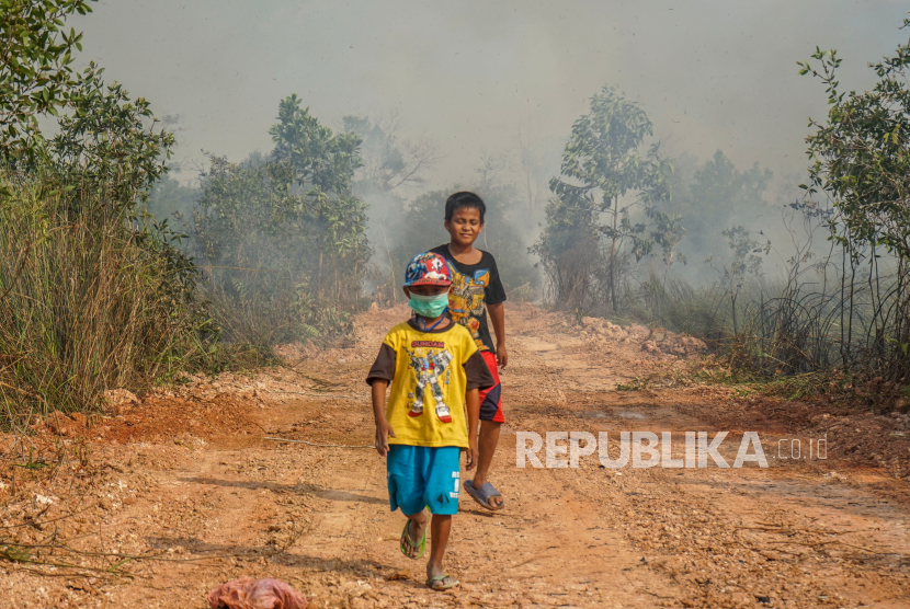 Dua bocah berjalan di dekat lokasi kebakaran lahan di Gambut, Kabupaten Banjar, Kalimantan Selatan, Jumat (6/10/2023). 