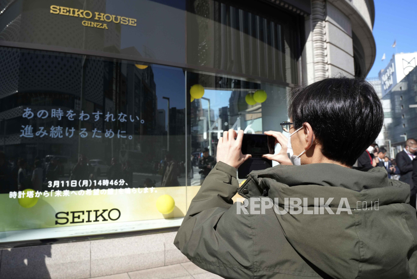 Seorang pejalan kaki mengambil foto tanda tersebut di sebuah toko untuk penghormatan tahunan bagi para korban bencana tahun 2011 Senin, (11/3/2024), di Tokyo.
