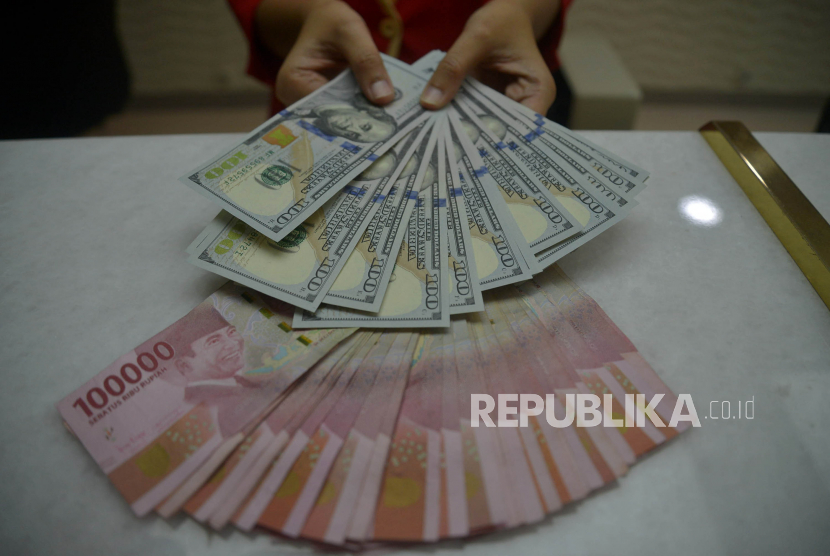 Petugas menunjukkan uang rupiah dan dolar AS di salah satu gerai penukaran mata uang asing di Jakarta, Kamis (29/9/2022) (ilustrasi).