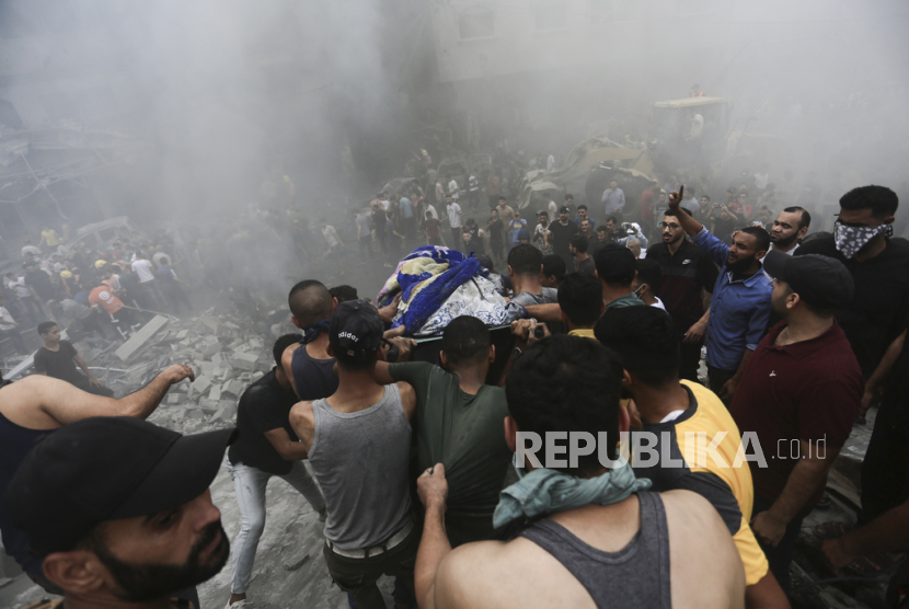 Warga Palestina mengeluarkan jenazah dari reruntuhan bangunan pasca serangan udara Israel di kamp pengungsi Jebaliya, Jalur Gaza, Senin,(9/10/2023).