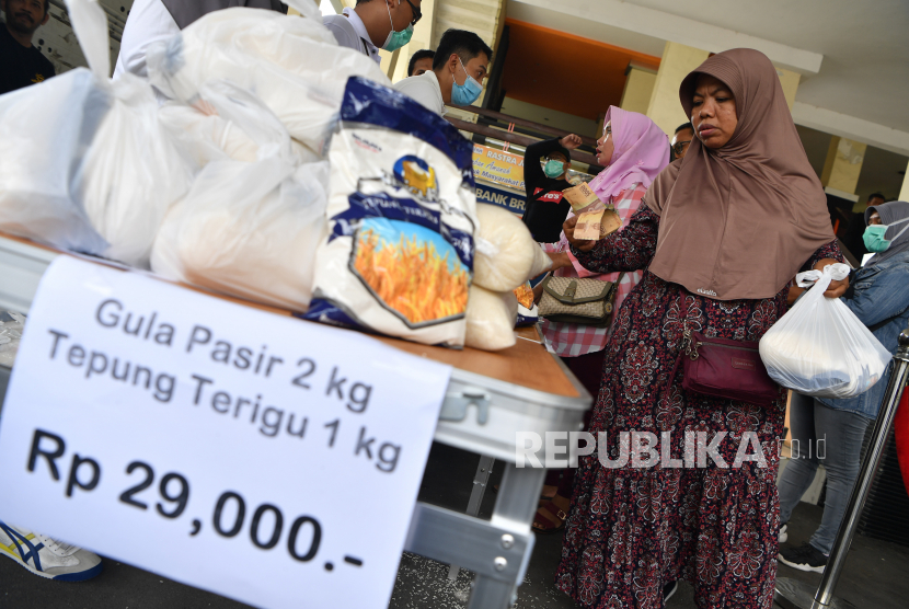 Warga mengantre untuk membeli beras dan gula pasir saat digelar operasi pasar murah di halaman Kantor Bulog Divre Jatim, Surabaya, Jawa TImur, Sabtu (21/3/2020). Pasar murah tersebut digelar guna mengantisipasi adanya 