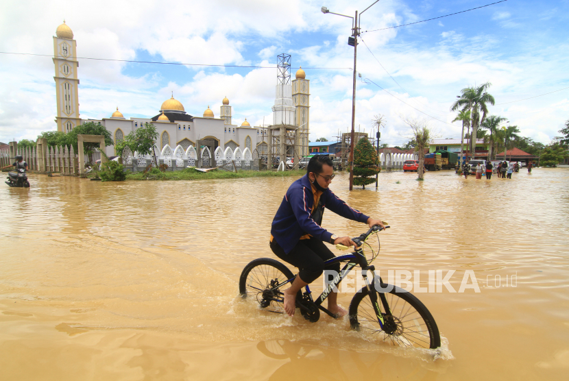 Seorang pesepeda melintasi jalan raya yang terendam banjir, di Kota Putussibau, Kabupaten Kapuas Hulu, Kalimantan Barat. Banjir yang melanda Putussibau secara merata menyebabkan warga tak bisa menunaikan shalat Id berjamaah, Kamis (13/5) 
