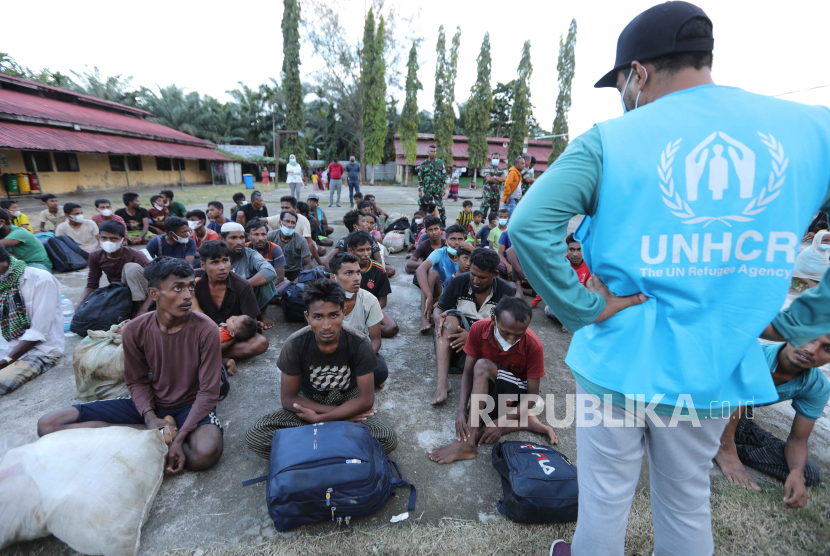 Anggota staf UNHCR berdiri di samping pengungsi Rohingya di dalam tempat penampungan sementara setelah mendarat di pantai di Desa Laweung, Pidie, Indonesia, 14 November 2023. 