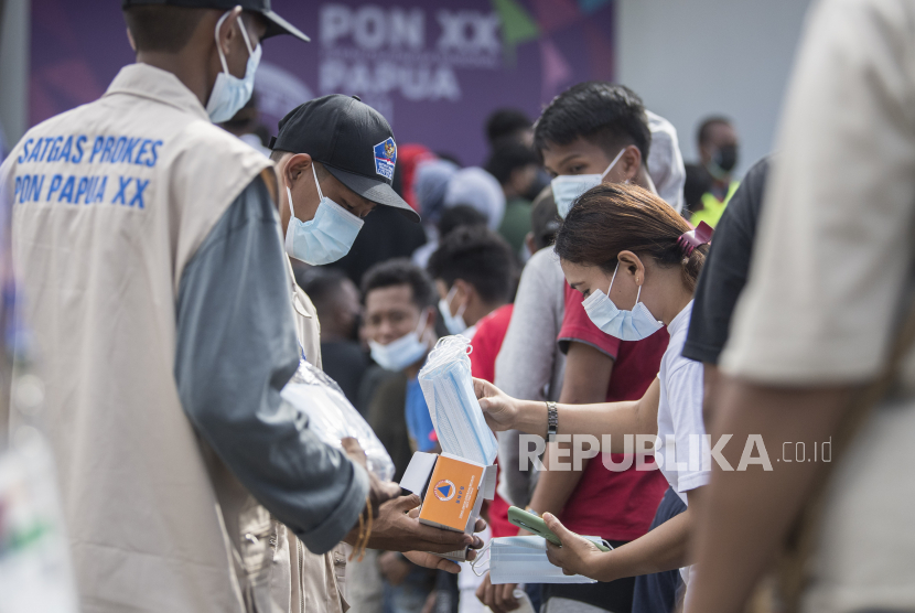 Satgas Prokes membagikan masker kepada warga yang mengantre untuk masuk menyaksikan pertandingan cabang olahraga futsal PON XX Papua di Gor SP 2, Kabupaten Mimika, Jumat (1/10/2021).  