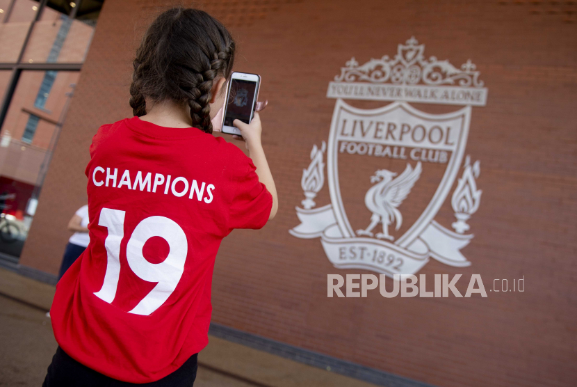 Seorang pendukung Liverpool FC muda mengambil gambar lambang timnya saat merayakan di luar stadion Anfield di Liverpool, Inggris, 