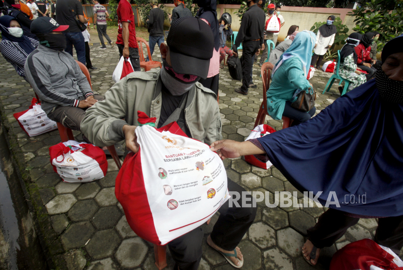 Warga menunjukkan paket sembako dari Presiden Jokowi yang disalurkan Kementerian Sosial di Kelurahan Pakansari, Cibinong , Kabupaten Bogor, Jawa Barat, Rabu (13/5/2020). Kementerian Sosial menyalurkan bantuan paket sembako untuk 70