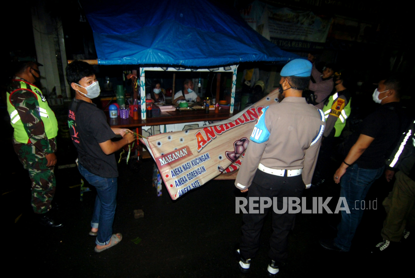 Personel TNI/Polri menutup paksa warung makanan saat razia Pelaksanaan Pembatasan Kegiatan Masyarakat (PPKM) di Tegal, Jawa Tengah, Sabtu (23/1/2021) malam. Razia PPKM gabungan TNI/Polri dan Satpol PP dengan membubarkan kerumuman masyarakat dan menutup paksa warung yang buka melewati pukul 21.00 WIB tersebut sebagai upaya pencegahan penyebaran COVID-19. 