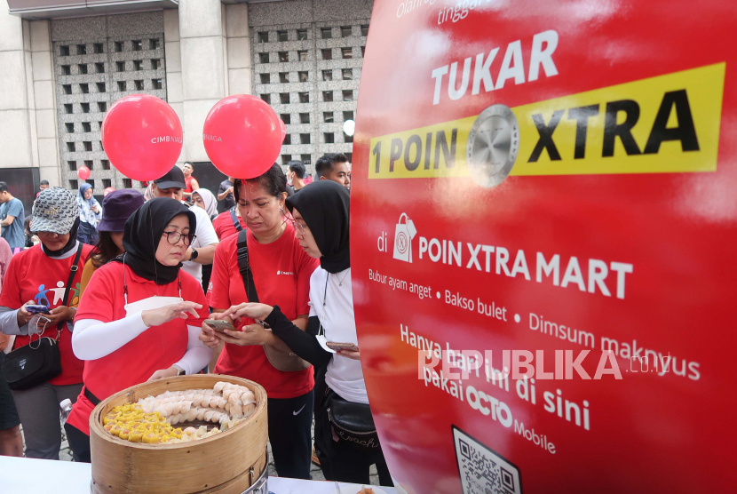 Nasabah melakukan pembayaran dengan menukar Poin Xtra melalui Digital Banking Super App OCTO Mobile usai mengikuti jalan santai bertajuk “Gerak Untuk Bumi” dalam rangka peringatan HUT 67 tahun CIMB Niaga di Jakarta, Ahad (25/9/2022). 
