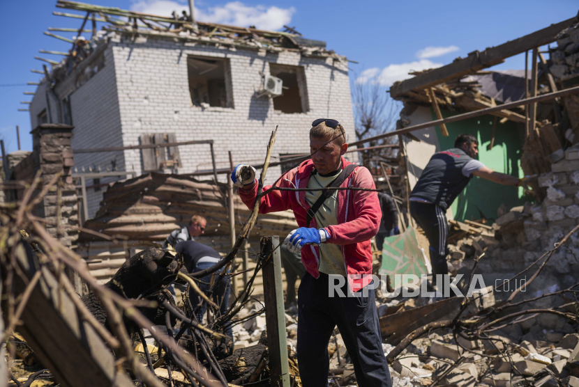 Penduduk setempat memindahkan puing-puing dari rumah-rumah yang hancur setelah roket Rusia, yang terkena sistem anti-pesawat Ukraina, menghantam daerah perumahan di Zaporizhzhia, Ukraina, Kamis, 28 April 2022. 