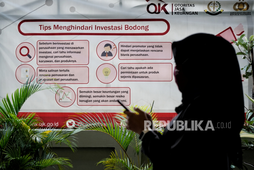 Warga melintas di dekat poster edukasi cara menghindari investasi bodong di kantor Otoritas Jasa Keuangan (OJK) Yogyakarta. 