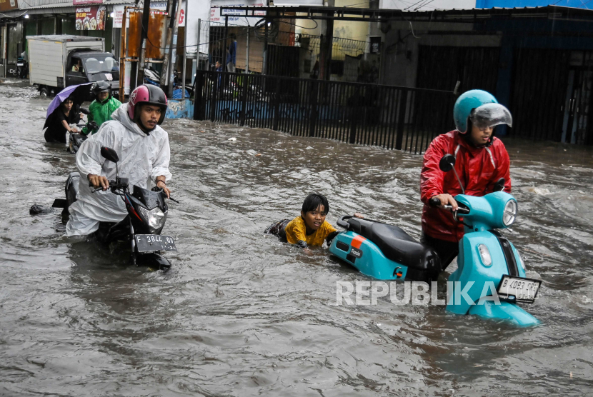 Warga membantu mendorong pengendara yang motornya mogok usai menerobos banjir. Sebanyak 12 RT di Jakarta masih tergenang banjir hingga Kamis siang.