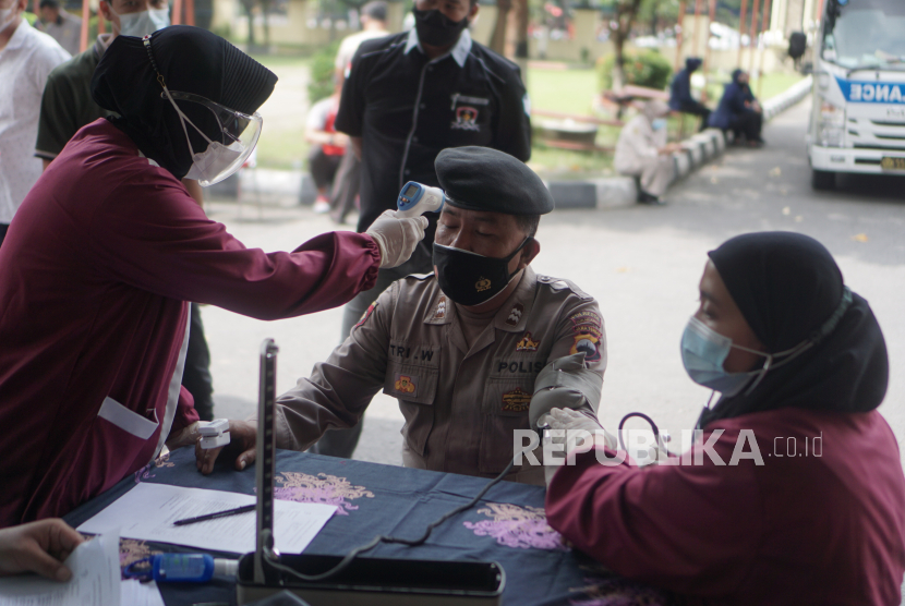 Petugas Kedokteran Kesehatan Kepolisian (Dokkes Pol) melakukan pemeriksaan kesehatan anggota polisi sebelum menerima vaksin Covid-19 Sinovac saat vaksinasi tahap dua di Polresta, Solo, Jawa Tengah, beberapa waktu lalu.