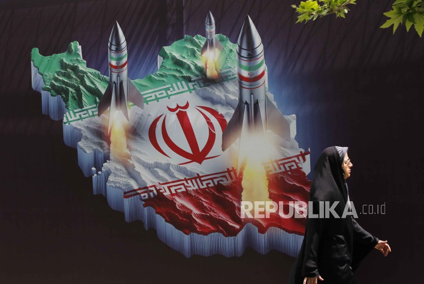 Seorang warga melintasi gambar rudal-rudal Iran yang merupakan kampanye anti-Israel di Teheran, 16 April 2024. 