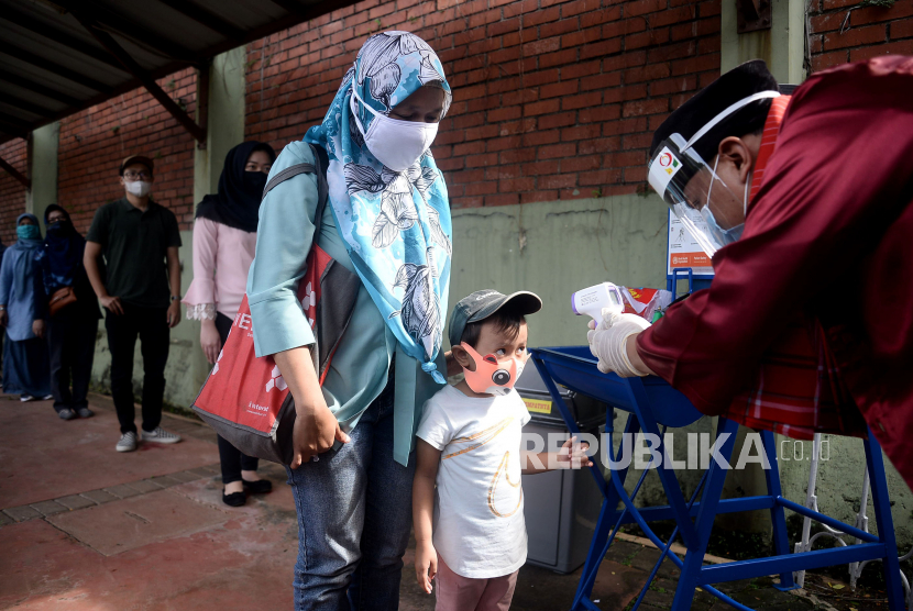 Petugas mengukur suhu tubuh wisatwan saat berlangsungnya simulasi normal baru di TMII, Jakarta, Kamis (4/6). Pengelola Taman Mini Indonesia Indah (TMII) telah mempersiapkan penerapan protokol kesehatan saat kehidupan normal baru atau 