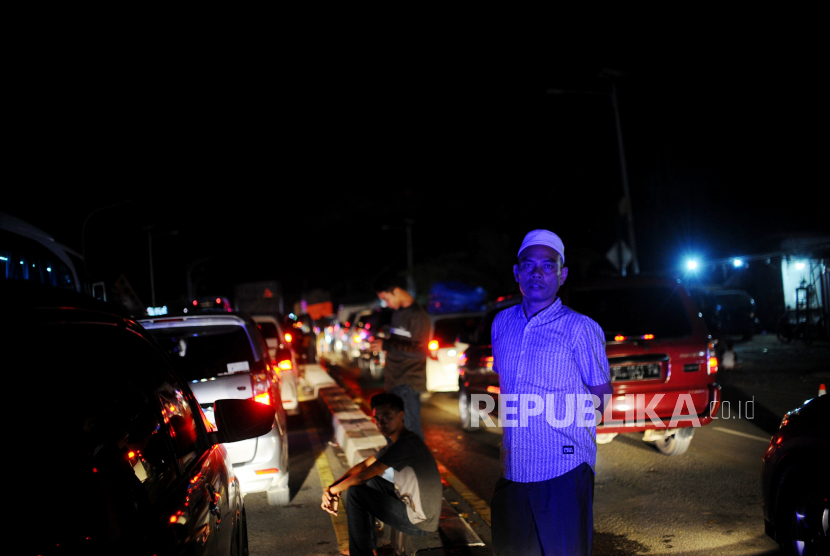 Pemudik beristirahat saat terjebak kemacetan di Jalan Alternatif Tol Merak Atasl,  Banten, Kamis (28/4/2022). Pada H-4 Hari Raya Idul Fitri 1443 Hijriah, volume kendaraan di gerbang Tol Merak menuju Pelabuhan Merak mengalami kenaikan signifikan yang berdampak pada kemacetan sepanjang 6 kilometer yang disebabkan sistem buka tutup di Jalan Cikuasa Atas, Pulomerak, Cilegon. ASDP Tambah Kapal Antisipasi Puncak Arus Mudik