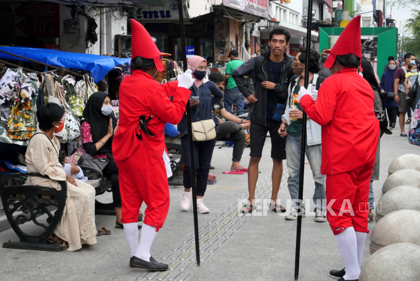 Petugas Jogoboro menggunakan pakaian prajurit mengingatkan pengunjung menggunakan masker di jalur pedestrian Malioboro, Yogyakarta.