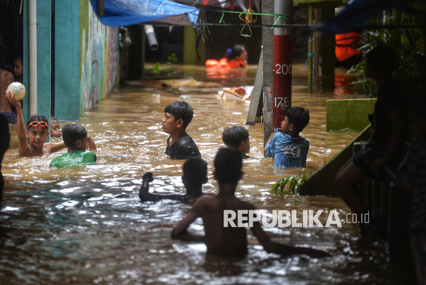 Anak-anak bermain saat banjir melanda permukiman warga di Kebon Pala, Kelurahan Kampung Melayu, Jatinegara, Jakarta Timur, Kamis (28/11/2024).