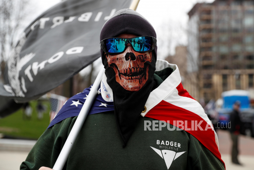 Dunia Catatkan 70 Juta Kasus Covid-19. Seorang pengunjuk rasa mengenakan masker bergambar tengkorak saat unjuk rasa memprotes kebijakan karantina di Wisconsin, Amerika Serikat.