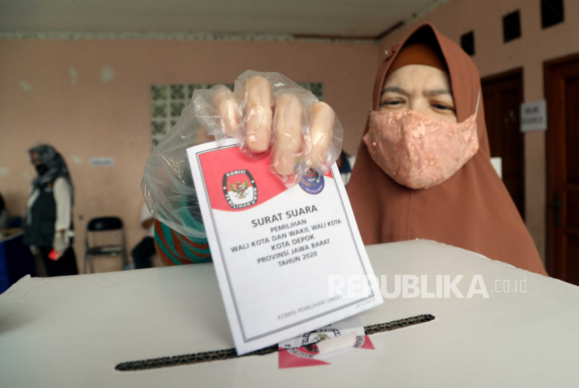  Wanita Muslim Indonesia memberikan suaranya di kotak suara di TPS selama Pilkada di tengah pandemi virus Corona, di Depok, Jawa Barat, Indonesia, 09 Desember 2020.