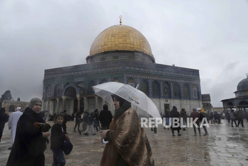  Seorang wanita Muslim berjalan dengan payung  di Masjid Dome of the Rock pada hari hujan yang dingin di kompleks Masjid Al-Aqsa di Kota Tua Yerusalem, Jumat (6/1/2023).