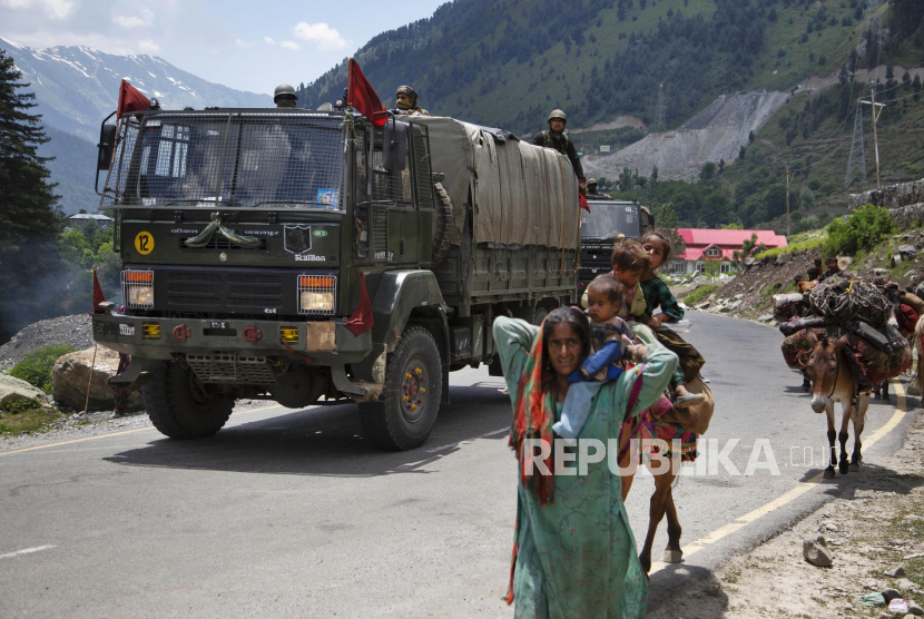Pengembara suku Bakarwal berjalan ketika konvoi tentara India bergerak di jalan raya Srinagar-Ladakh di Gagangeer, India, Rabu (17/6). Pasukan keamanan India mengatakan tidak ada pihak yang melepaskan tembakan dalam bentrokan di wilayah Ladakh Senin malam