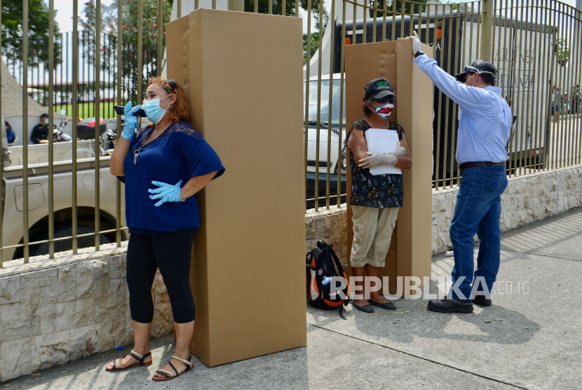 Sejumlah keluarga menunggu didekat peti mati kardus untuk menguburkan jenazah di pemakaman Jardines de la Esperanza di Guayaquil, Ekuador, Senin (6/4). Provinsi Guayas dan kota utama Guayaquil adalah pusat wabah Covid-19 dengan sekitar 66 persen kasus koronavirus di Ekuador