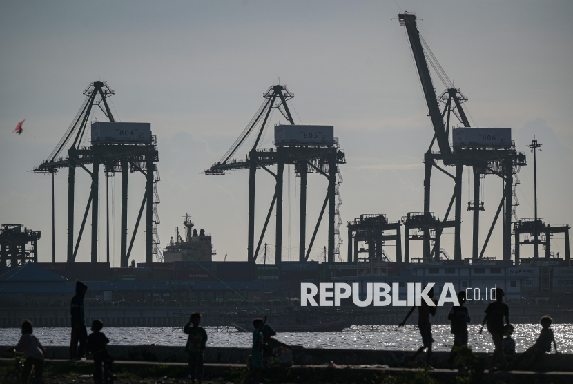 Siluet sejumlah anak bermain dengan latar belakang aktivitas bongkar muat peti kemas di New Priok Container Terminal One, Jakarta, Selasa (1/7/2025). 