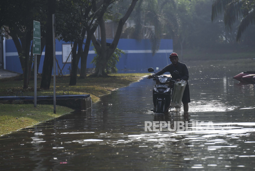 Pengendara mendorong motornya saat melintasi banjir rob di kompleks Pantai Mutiara, Penjaringan, Jakarta Utara (ilustrasi).