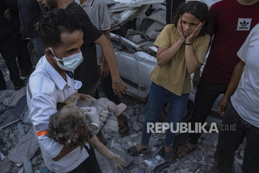 Petugas medis mengevakuasi jenazah seorang anak dari reruntuhan bangunan setelah serangan udara Israel di Khan Younis, Jalur Gaza, Sabtu, 21 Oktober 2023.