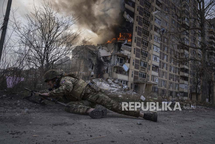 Seorang tentara Ukraina berlindung di depan gedung yang terbakar akibat serangan udara Rusia di Avdiivka, Ukraina, Jumat (17/3/2023)..