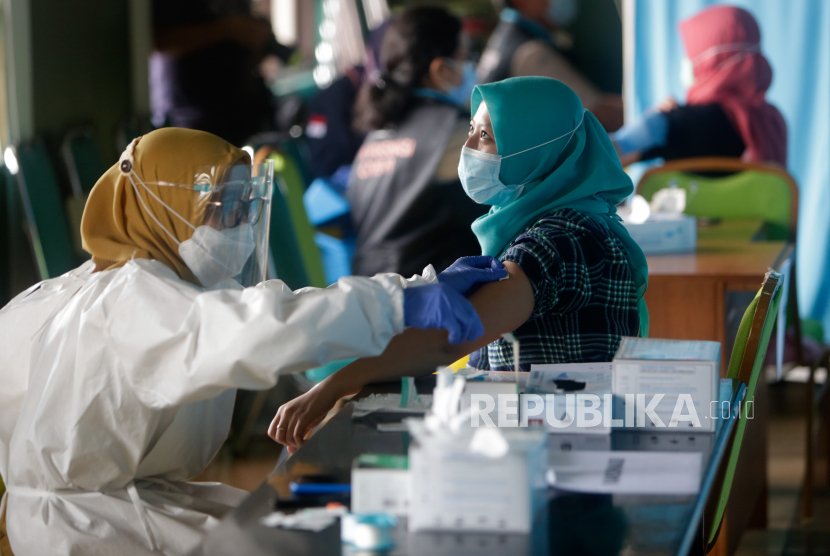 Seorang dokter menyuntikkan vaksin Covid-19 Sinovac kepada petugas kesehatan di Jakarta, 15 Februari 2021. Pemberian dosis ketiga vaksin Covid-19 untuk tenaga kesehatan dianggap perlu mengingat tingkat paparan virus yang lebih tinggi di rumah sakit. 