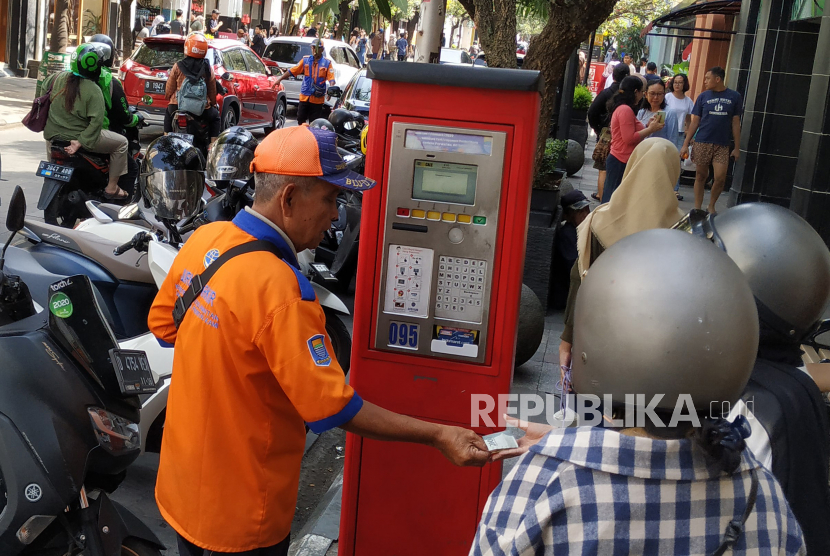 Juru parkir (jukir) membantu warga membayar retribusi melalui mesin parkir di kawasan Jalan Braga, Kota Bandung, Jawa Barat, Senin (5/5/2023). 