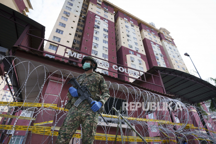 Seorang tentara bersenjata berjaga di luar area perumahan kepadatan tinggi yang ditempatkan di bawah perintah kontrol gerakan yang ditingkatkan (EMCO) karena peningkatan drastis jumlah kasus COVID-19 yang tercatat di Sunway, di pinggiran Kuala Lumpur, Malaysia, Jumat, 2 Juli , 2021. 