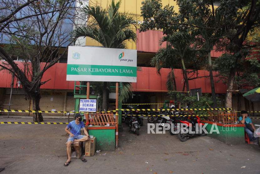 Warga duduk di depan papan nama Pasar Kebayoran Lama, Jakarta, Kamis, (18/6/2020). Pasar Kebayoran Lama ditutup sementara setelah 14 orang pedagang dinyatakan positif COVID-19