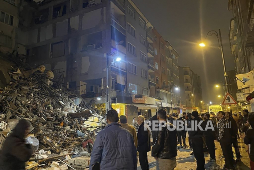 Warga berkumpul di depan bangunan yang roboh akibat diguncang gempa di Pazarcik, Turki, Senin (6/2/2023). Gempa besar berkekuatan 7,8 mengguncang tenggara Turki Senin (6/2/2023) pagi WIB. Kerusakan akibat gempa dilaporkan terjadi di beberapa Provinsi Turki, dan tim penyelamat diterjunkan untuk menolong korban gempa.