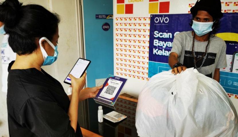 Transaksi non tunai pelanggan laundry di komunitas Tasawuf Underground. Peserta program Kartu Prakerja ini telah memilih OVO untuk mencairkan dana insentif program Prakerja dan memulai usaha dengan mengakses pasar digital. (Sufri Yuliardi)