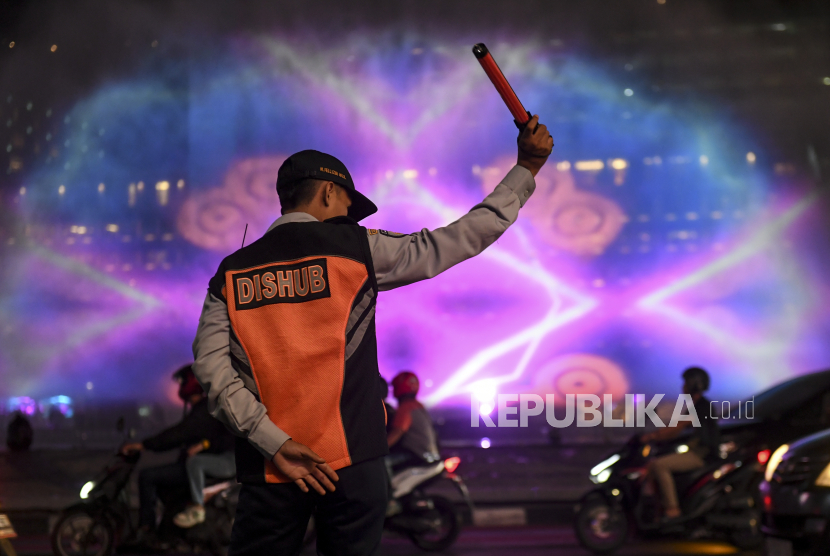 Petugas mengatur lalu lintas di dekat water screen perayaan malam tahun baru di Bundaran HI, Jakarta, 