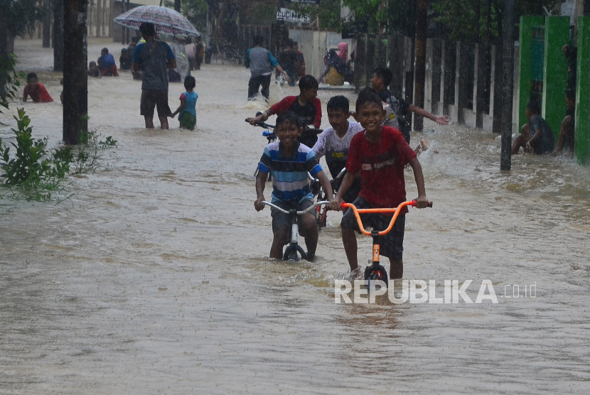 Sejumlah bocah bermain sepeda di jalan yang tergenang banjir di Desa Kesambi, Mejobo, Kudus, Jawa Tengah, Selasa (19/1/2021). Akibat intensitas hujan yang tinggi sejak dua hari terakhir serta meluapnya sejumlah sungai di wilayah setempat menyebabkan ratusan rumah dan jalan utama terdampak banjir dengan ketinggian 30-80 centimeter.