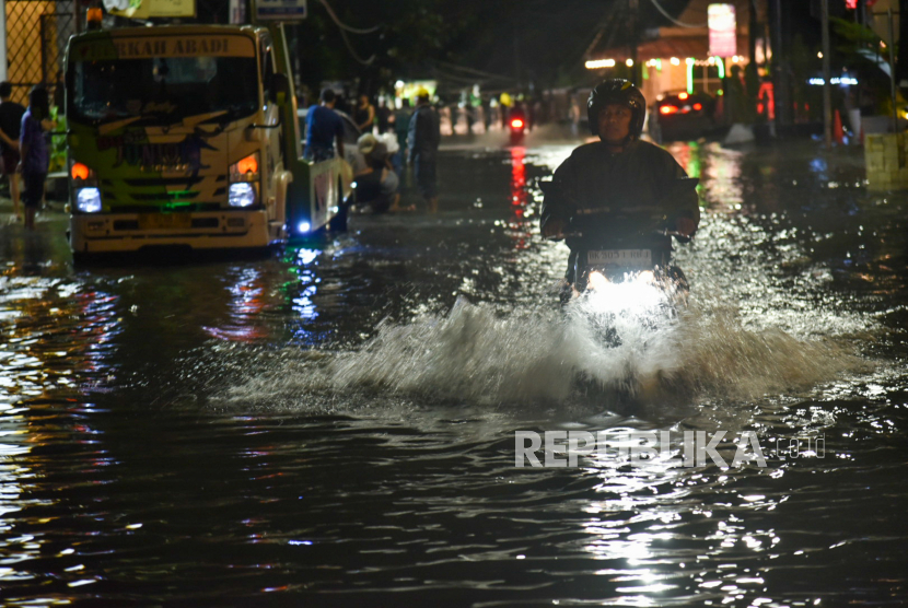 Pengendara sepeda motor melintasi jalan yang terendam banjir di Medan, Sumatera Utara, Senin (25/9/2023).